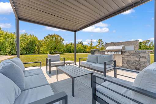 A patio with grey couches and a table under a roof.