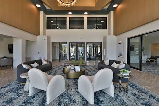 A modern living room with a large rug and white chairs.
