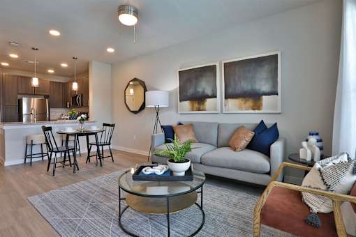 A modern living room with a glass coffee table and a grey sofa.