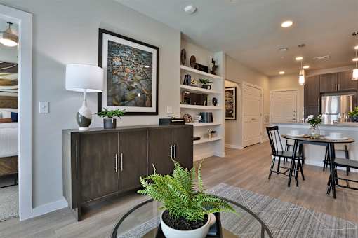 A modern living room with a wooden cabinet, a potted plant, and a framed picture on the wall.