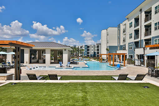 A swimming pool surrounded by lounge chairs and a building in the background.