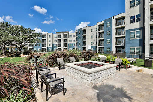 A sunny day at a residential complex with a fountain in the middle of a patio.