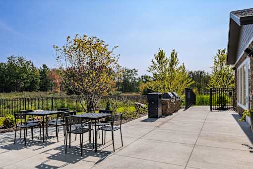 A patio with a table and chairs is surrounded by trees.