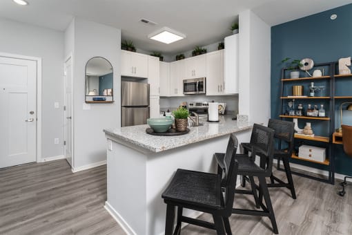 a kitchen with a counter with chairs and a
