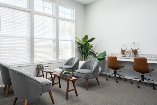 a living room with chairs and a table and windows