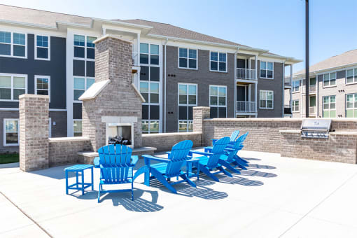 a patio with blue chairs and a fire pit