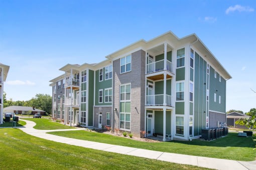 an exterior view of an apartment building with a sidewalk