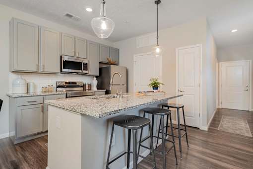 A kitchen with a granite countertop and bar stools.