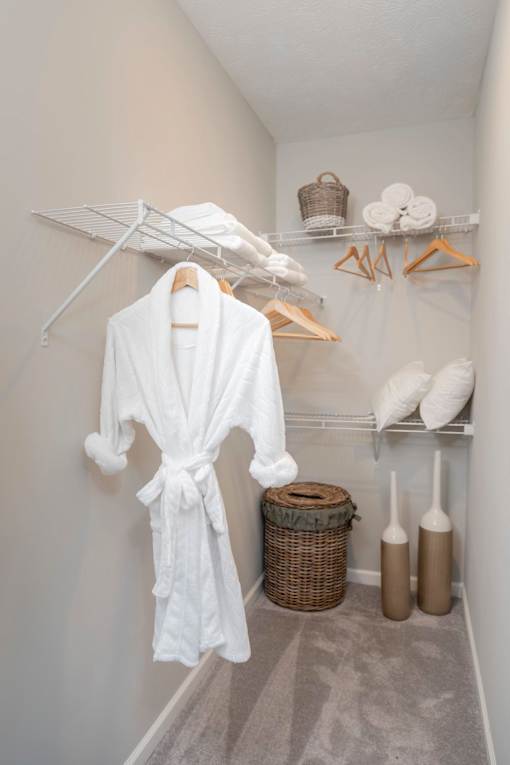 A white robe is hanging on a rack in a small room.