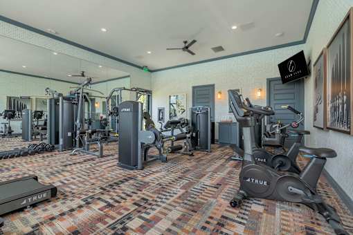 A gym with a variety of equipment including treadmills, weights, and exercise machines.