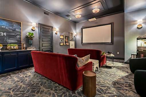 A living room with a red couch and a grey car poster on the wall.