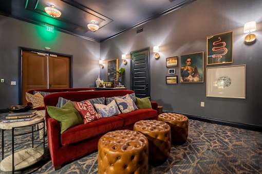 A living room with a red couch, a coffee table, and a green exit sign on the wall.