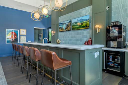 A row of brown leather bar stools are in front of a bar.