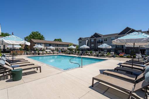 A large swimming pool surrounded by sun loungers and umbrellas.