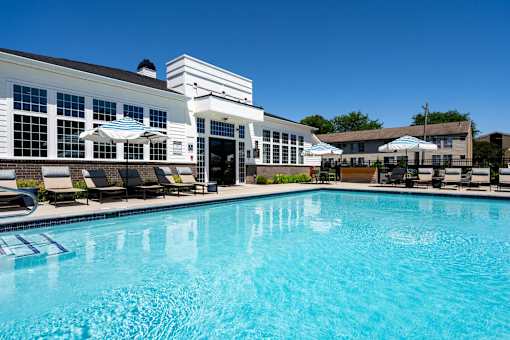 A swimming pool in front of a building with a white facade.