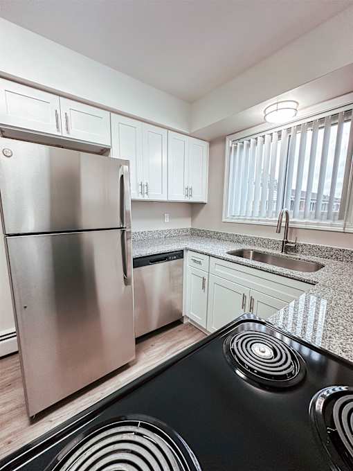 A modern kitchen with a stainless steel refrigerator and black stove top.