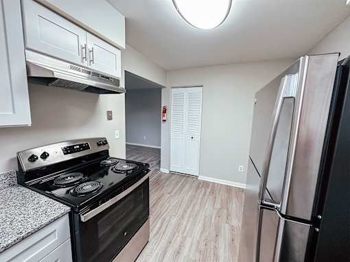 A kitchen with a black stove top oven and a refrigerator.