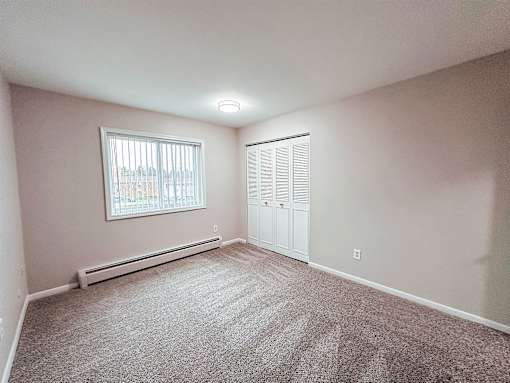 A room with a window and a carpeted floor.