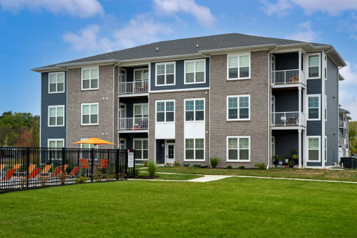 an apartment building with a green lawn and a fence