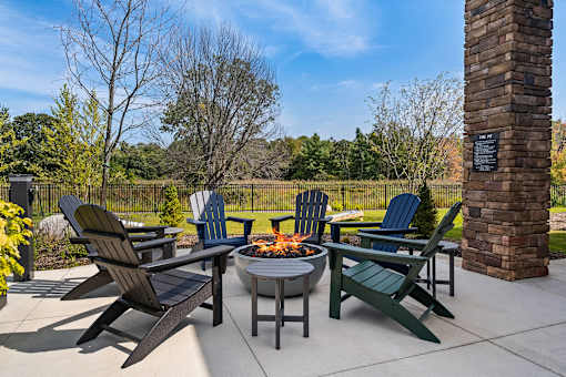 A patio with a fire pit and chairs.