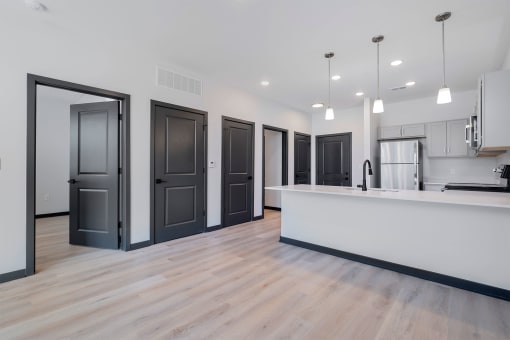 a kitchen and living room with a white counter top and black doors