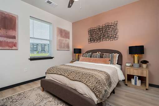 A bedroom with a large bed and two lamps.