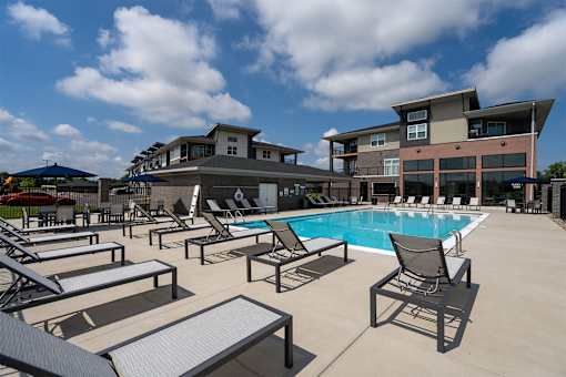 A pool area with sun loungers and a building in the background.