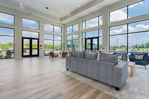 A spacious living room with a grey sofa and wooden flooring.