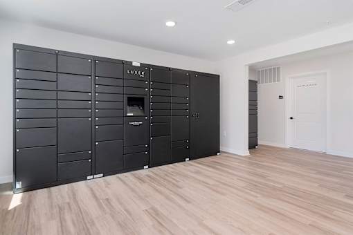A large, black, LUXE branded wardrobe in a room with wooden flooring.