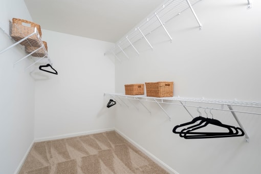 a walk in closet with white walls and white shelves