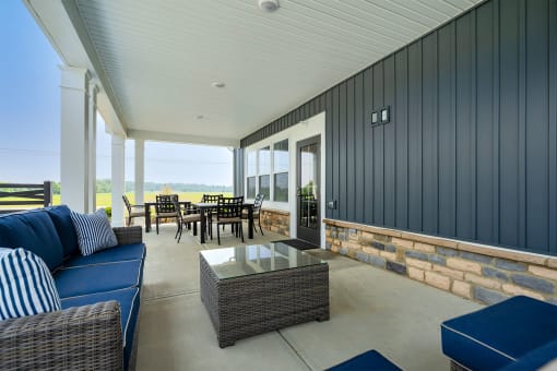 a covered patio with a blue couch and a glass coffee table