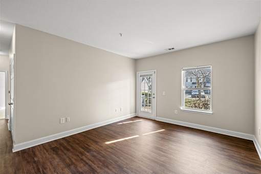 A room with a wooden floor and a window with a picture of a house on it.