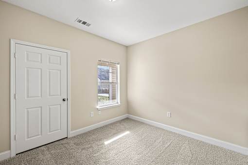 A room with a white door and a window with a view of a building outside.