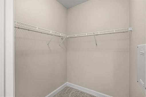 A white closet with a white shelf and a white door.