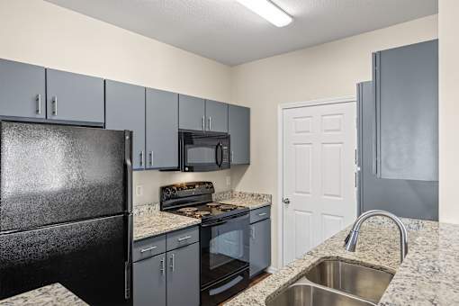 A kitchen with a black refrigerator and a white door.