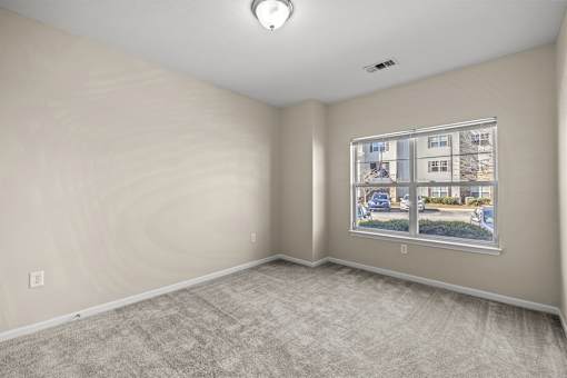 A room with a window showing a view of a street with cars and houses.
