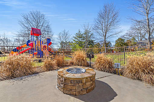 A playground with a red and blue slide and a circular stone structure in the middle.