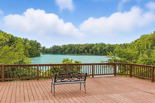 A bench sits on a wooden deck overlooking a lake.
