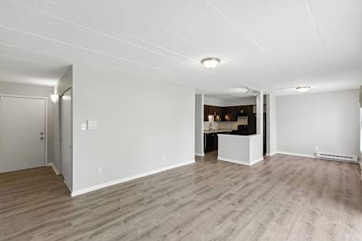 A spacious room with wooden flooring and white walls.