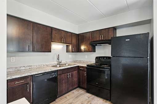 A kitchen with black appliances and wooden cabinets.