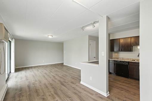 A large empty room with a kitchen area in the background.