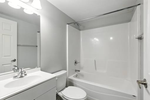 A white bathroom with a toilet, sink, and bathtub.