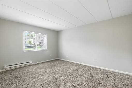 A room with a window and a carpeted floor.