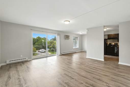 A spacious room with wooden flooring and sliding glass doors.