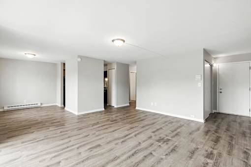 A spacious room with wooden flooring and white walls.