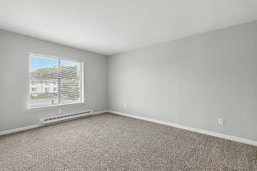 A room with a carpeted floor and a window overlooking a parking lot.