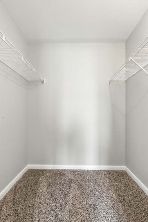 A room with a carpeted floor and two white shelves.