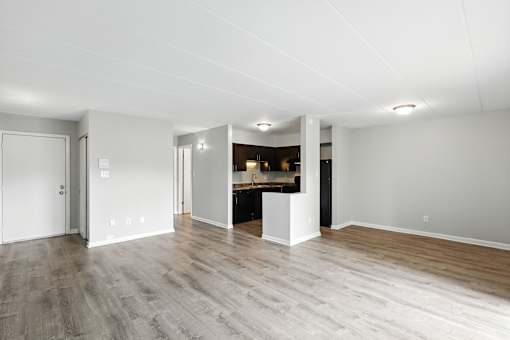 A large empty room with a kitchen area in the background.