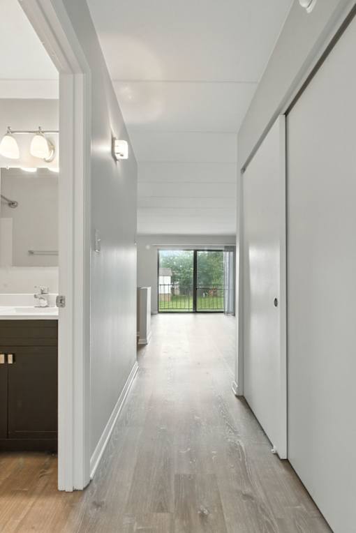 A long hallway with white walls and wood floors.