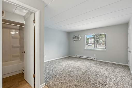 A room with a carpeted floor and a window showing a building outside.